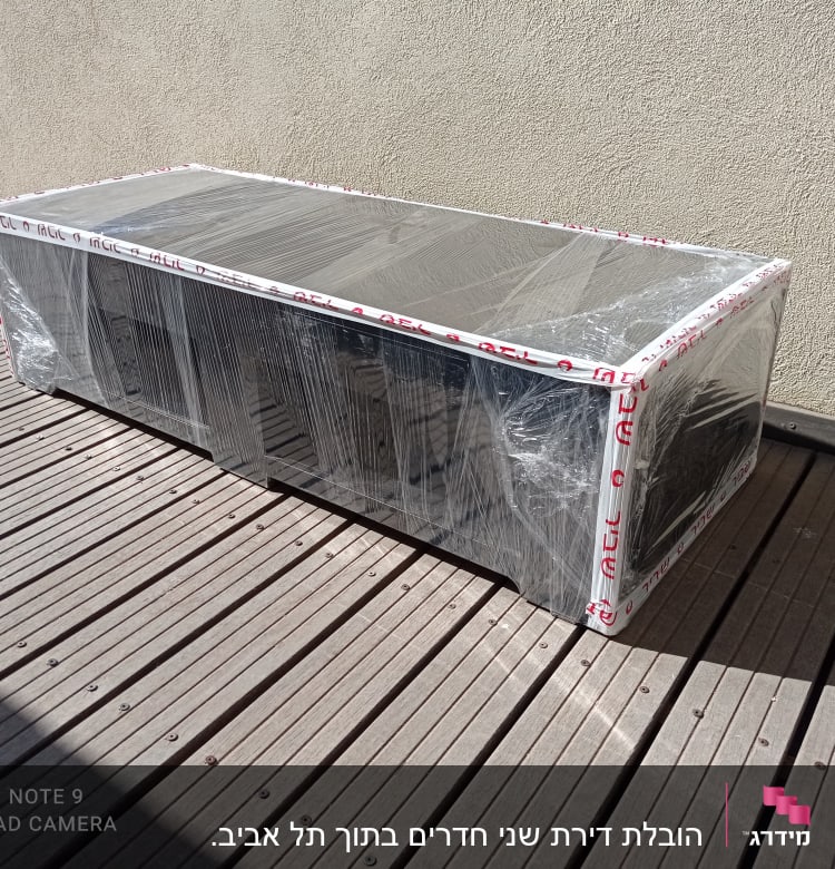 ארגז עטוף בניילון על רצפת עץ